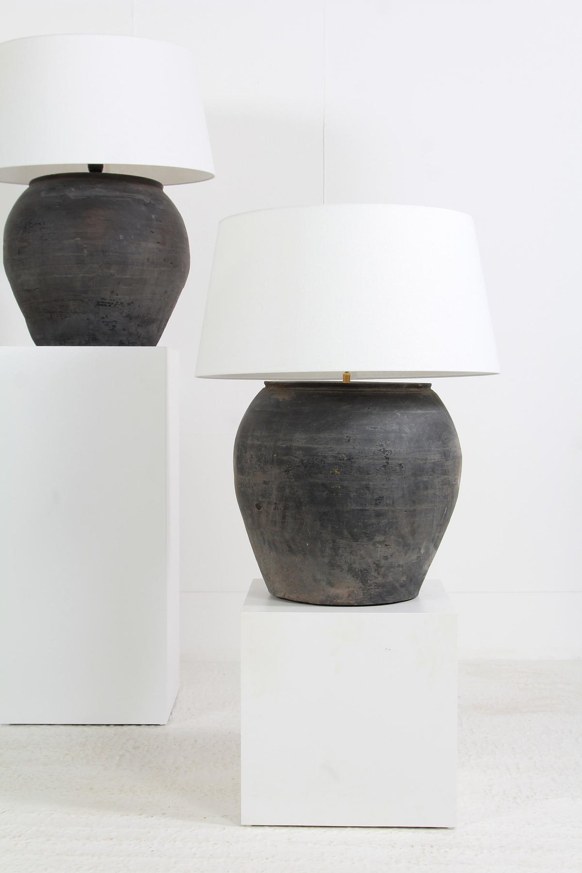 NEAR PAIR OF HUGE CHINESE BLACK POTTERY LAMPS WITH WHITE LINEN SHADES